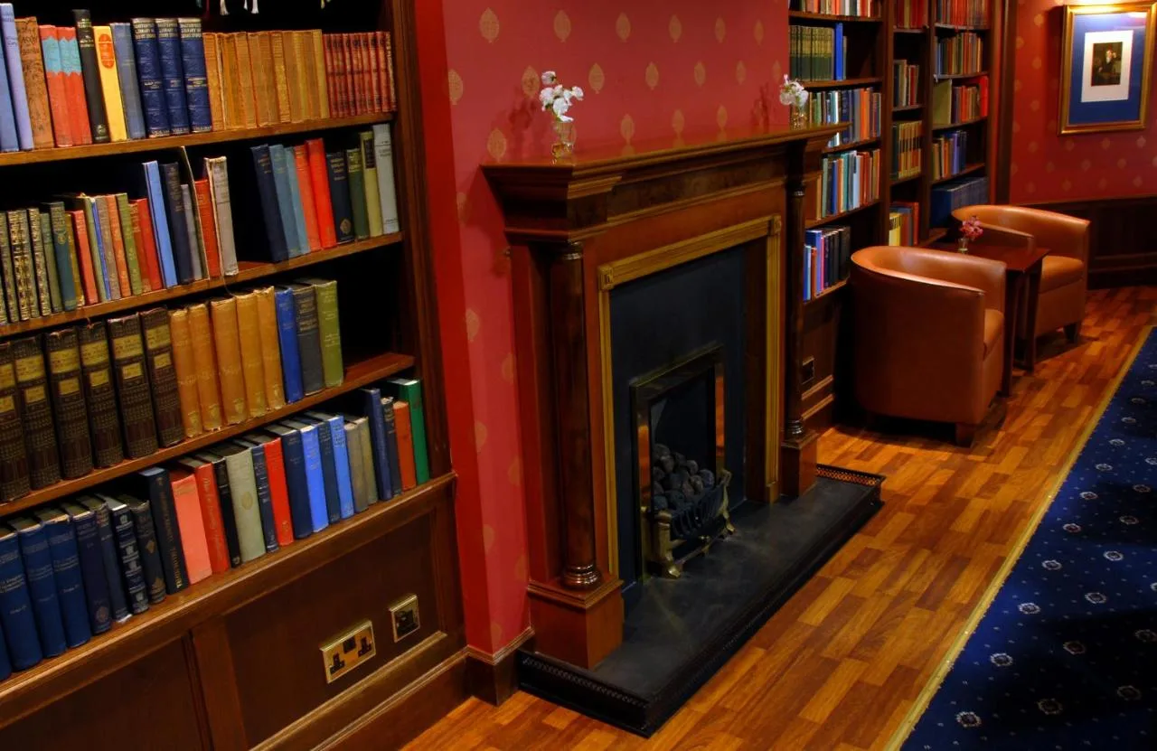 a fireplace in the middle of a library with books at The Craighaar Hotel in Aberdeen
